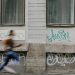 Blurred motion of a woman running past a graffiti-covered urban wall. Captures dynamic energy.